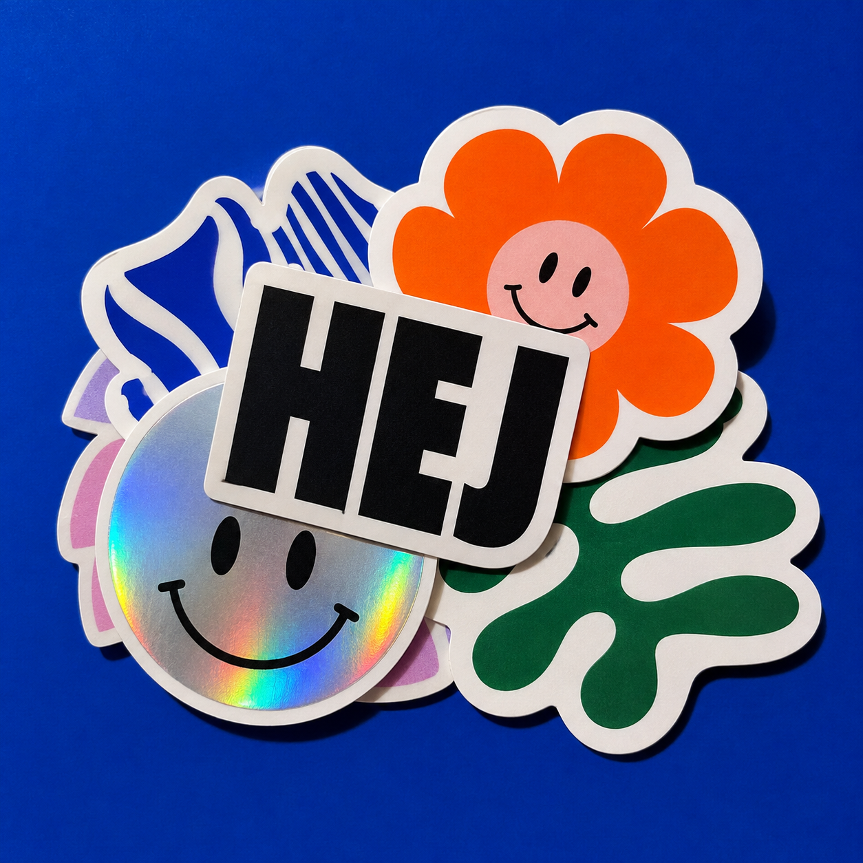 Originale stickers med HEJ, orange blomst og holografisk smiley på blå baggrund